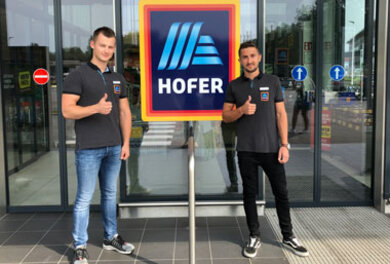 Zwei ehemalige HOFER Lehrlinge und heutige Filialleiter stehen vor der HOFER Filiale
