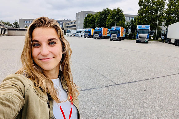 Selfie mit Managementpraktikantin Josepha vor dem Fuhrpark der Logistik