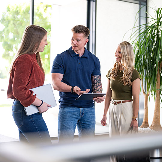 eine Gruppe aus drei Personen im Gespräch beim Eingang der Firma