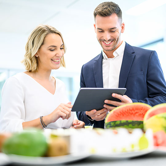 zwei Mitarbeiter protokollieren Ergebnisse einer Verkostung von Obst in einem Tablet