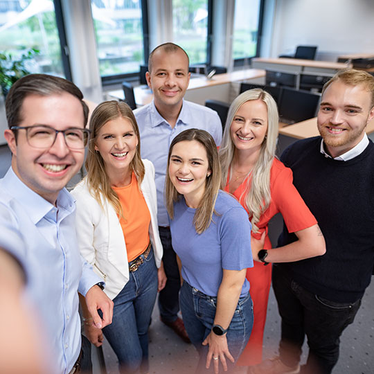 sechs Kolleginnen und Kollegen machen ein Selfie im Büro