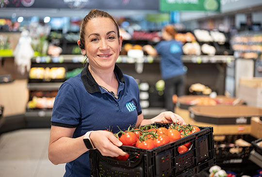 Verkaufsmitarbeiterin präsentiert Gemüse